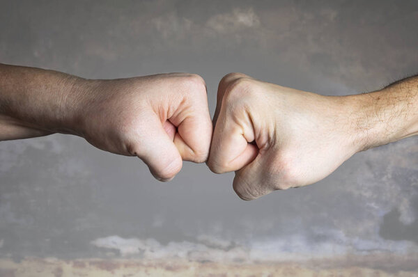 Close up clash of two fists on dramatic background. Concept of confrontation, competition etc.