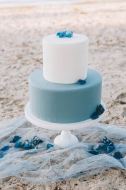 Blue two-tiered wedding cake with a romantic quote on a beach clipart