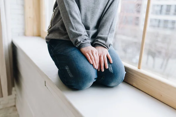 Young caucasian European woman sitting on windowsill, hands in her lap — 스톡 사진