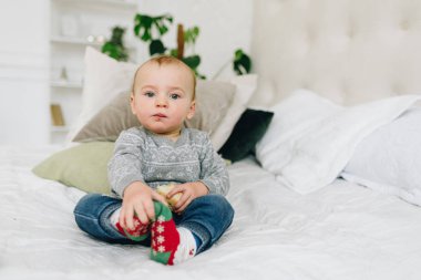 Sevimli küçük yürümeye başlayan çocuk düz görünümlü bir aperatif tutarak yatakta oturan