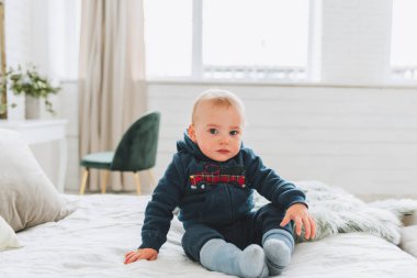 Sevimli küçük yürümeye başlayan çocuk yatakta oturan