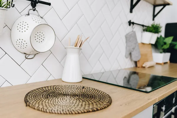 Ευρύχωρη, μοντέρνα σκανδιναβική κουζίνα με λευκά πλακάκια και μαύρες συσκευές. Φωτεινό δωμάτιο. Μοντέρνο εσωτερικό. Φουρνάκι, σόμπα, πάγκο, σουρωτήρι. — Φωτογραφία Αρχείου