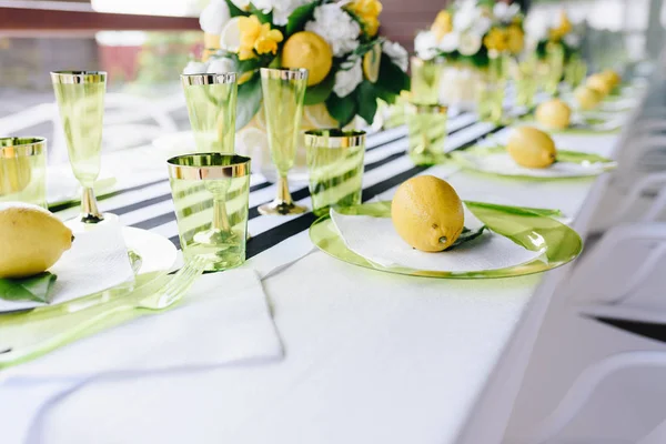 Τραπέζι δεξιώσεων διακοσμημένο με ολόκληρα λεμόνια σε πιάτα και ριγέ τραπεζομάντιλο — Φωτογραφία Αρχείου