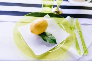 Beyaz peçete ve açık yeşil cam plaka üzerinde bir yaprak ile yakın çekim bütün limon