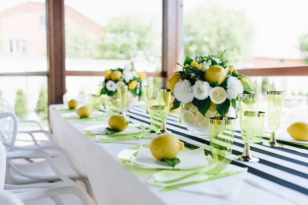Καλοκαίρι τραπέζι Συμπόσιο σε βεράντα με ριγέ τραπεζομάντιλο διακοσμημένο με ολόκληρα λεμόνια και μπουκέτα από λουλούδια και λεμόνια — Φωτογραφία Αρχείου