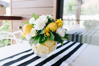 Cam vazoda beyaz ve sarı çiçekler ve limontaze bir modern buket 