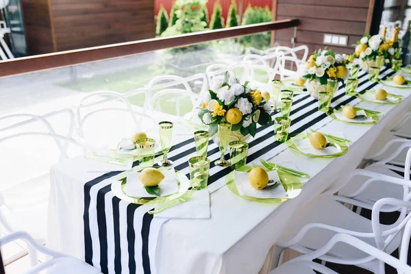 Ένα όμορφο τραπέζι δεξιώσεων σε βεράντα διακοσμημένο με λουλούδια και ολόκληρα λεμόνια — Φωτογραφία Αρχείου
