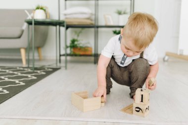 Odanın zemininde tuğla oynayan sevimli bir çocuk