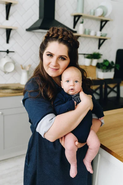 Una hermosa mujer abrazando a su bebé en la cocina — Foto de Stock
