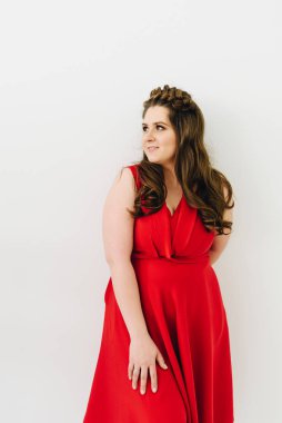 Uzun saçlı kırmızı moda elbise giyen genç bir kadın uzağa bakıyor 