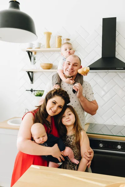 En ung lycklig kaukasisk familj med tre barn i köket — Stockfoto