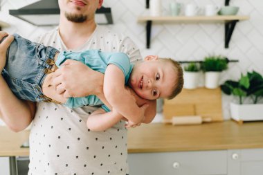 Komik bir küçük kafkas çocuk kollarında babası ile oynarken ve gülümseyerek