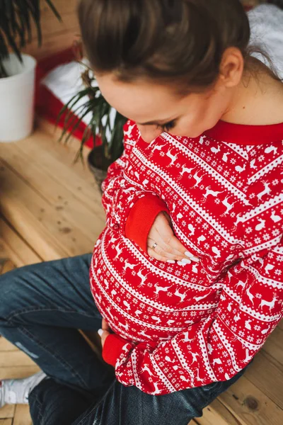 Jovem grávida sentada e olhando para a barriga — Fotografia de Stock