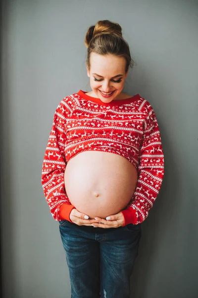 Jovem grávida de pé e olhando para a barriga — Fotografia de Stock