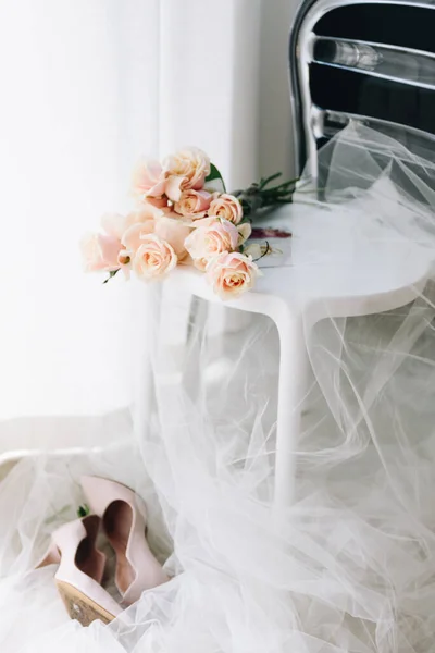 Foto femminile della sposa che si prepara la mattina del suo matrimonio: bel mazzo di rose su una sedia con velo, paio di scarpe da sposa — Foto Stock