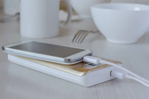 Power bank charges cell phone on the kitchen table