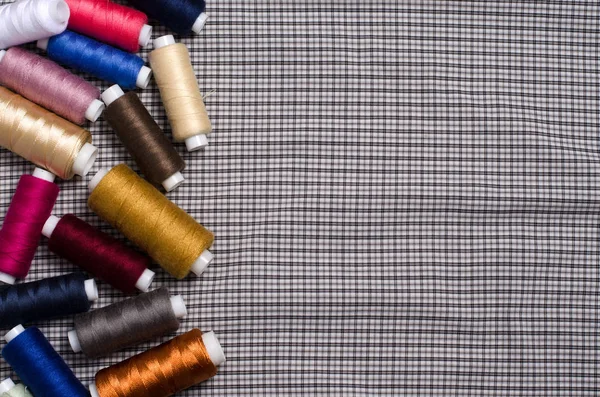 缝制工具和附件 彩色缝纫线在灰色纺织品背景 平顶视图 — 图库照片