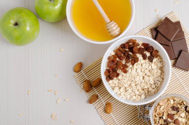 Bambu dan masa örtüsü üzerinde üzümlü yulaf ezmesi. Tatlım, çikolata, badem, granola. Düz üstten görünüm