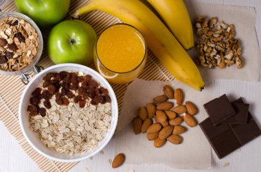 Sağlıklı gıda. Meyve, ev yapımı granola, fındık, çikolata, yulaf ezmesi, beyaz bir tablo portakal suyu. Düz üstten görünüm