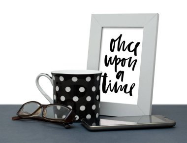 Bir zamanlar. El yazısı yazıt çerçeve içinde. Modern hat. Kahve fincanı, Gözlük, cep telefonu. Yakın çekim