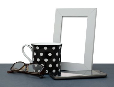 Beyaz fotoğraf çerçevesi, kahve fincanı, Gözlük, cep telefonu. Metin için arka plan