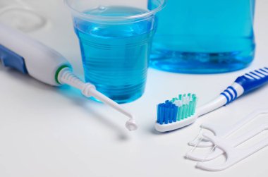 Diş sözlü irrigator, diş fırçası, diş ipi, gargara. Beyaz bir arka plan üzerinde. Yakın çekim