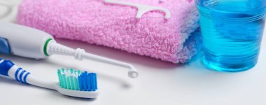 Dişlerle ilgili sağlık bilgisi. Diş fırçası, diş macunu, pembe havlu, diş ipi, oral irrigator. Yatay fotoğraf. Yakın çekim