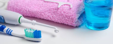 Dental hygiene. Toothbrush, mouthwash, pink towel, dental floss, oral irrigator. Horizontal photo. Close up clipart