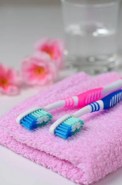 Twee Roze Tandenborstels Een Roze Handdoek Water Een Bekerglas Van — Stockfoto