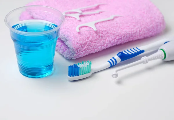 Dişlerle ilgili sağlık bilgisi. Diş fırçası, diş macunu, pembe havlu, diş ipi, oral irrigator. Yakın çekim