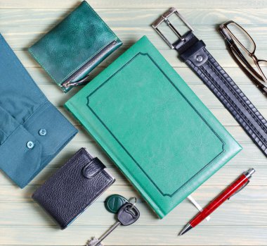 Erkek aksesuarlar. Kravat, yeşil defter, Gözlük, çanta, iş kart sahibi. Ahşap arka plan azaltılmış. Düz üstten görünüm.