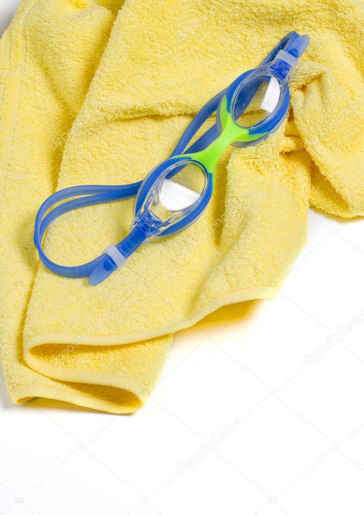 Blue swimming goggles on a yellow towel. Space for text. Vertical phot
