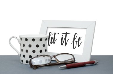 Varsın olsun. El yazısı yazıt çerçeve içinde. Kahve fincanı, Gözlük, kalem. Yakın çekim