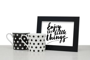 Küçük şeylerin tadını çıkarın. El yazısı metin. Modern hat. Siyah ahşap çerçeve metin için. Siyah ve beyaz kahve Kupası tablo. Yakın çekim, beyaz arka plan
