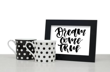 Gerçekleşecek bir hayal. El yazısı metnini, ilham alıntı olduğunu. Modern hat. Siyah ahşap çerçeve. Siyah ve beyaz kahve Kupası tablo. Yakın çekim, beyaz arka plan