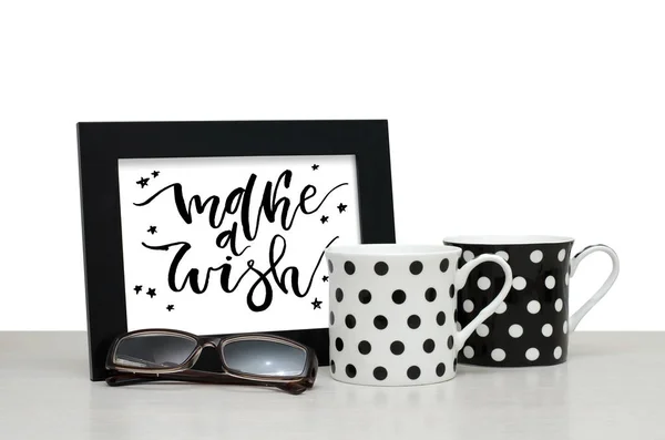 Make a wish. Handwritten inscription in the frame. Modern calligraphy. Coffee Cup, glasses. Close-up