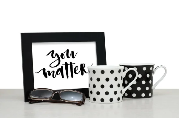 You matter. Handwritten inscription in the frame. Modern calligraphy. Coffee Cup, glasses. Close-up