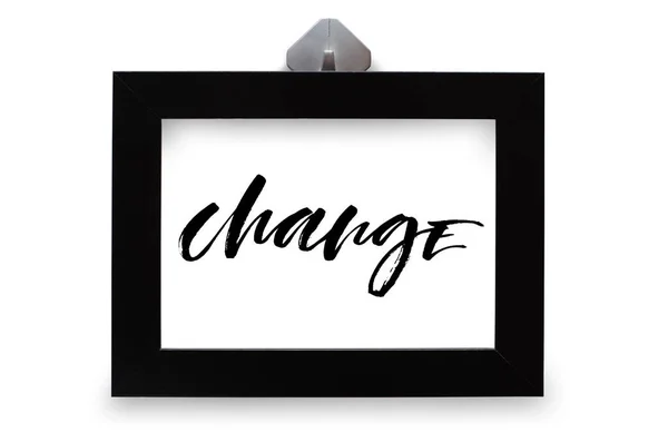 Change. Handwritten text, inspirational quote. Modern calligraphy. Black wooden frame. Close-up, white background