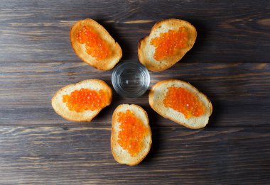 Beş sandviç somon havyar ile. Bardak votka. Koyu ahşap arka plan