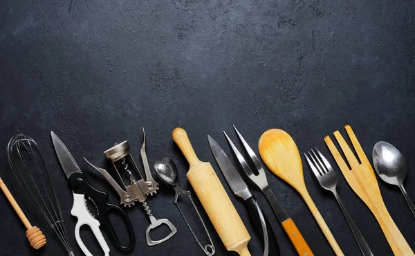 Ahşap ve metal mutfak gereçleri. Yemek pişirmek için aletler. Karanlık arka plan. Düz yatıyordu. Kopyalama alanı