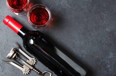 Bardakta kırmızı şarap, bir şişe şarap, tirbuşon. Koyu arka plan.