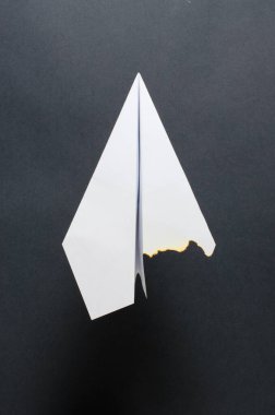 Yanmış kanadı olan kağıt bir uçak. Karanlık arka plan. Uçakta yangın ya da kaza konsepti..