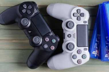 İzhevsk, Rusya - 17 Ekim 2019: Beyaz ve siyah joystick oyun konsolu Playstation. Çoklu Ps4 oyunu. Mavi tahta arkaplan