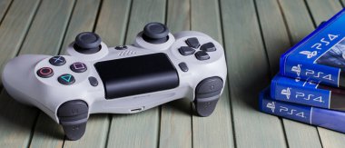 İzhevsk, Rusya - 17 Ekim 2019: Beyaz joystick oyun konsolu Playstation. Çoklu Ps4 oyunu. Mavi tahta arkaplan.
