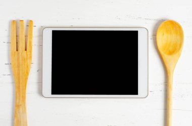 Tablet bilgisayar ve ahşap arka planda pişirme bataryası. Uzayı kopyala Yemek tarifi kavramı