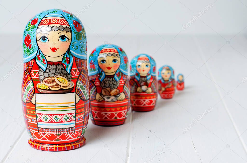 Five red matryoshka. Traditional Russian toy. Copy space. White wooden background.