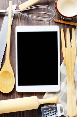 Kahverengi ahşap arka planda bir tablet bilgisayar ve pişirme bataryası. Uzayı kopyala Yemek tarifi kavramı.