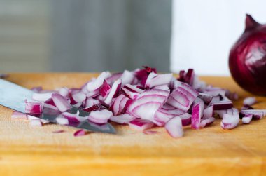 Kırmızı soğan dilimlenmiş. Sarı kesme tahtasında pişirme işlemi. Seçici odak