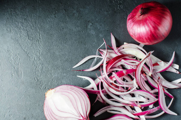 Red onion and sliced onion on a wooden chopping Board. Side view.