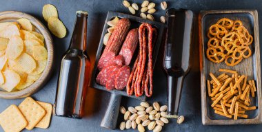 Bira şişelerinde bira ve bira için tuzlu atıştırmalıklar. Gri beton arka plan. Arkadaşlar için bir parti konsepti